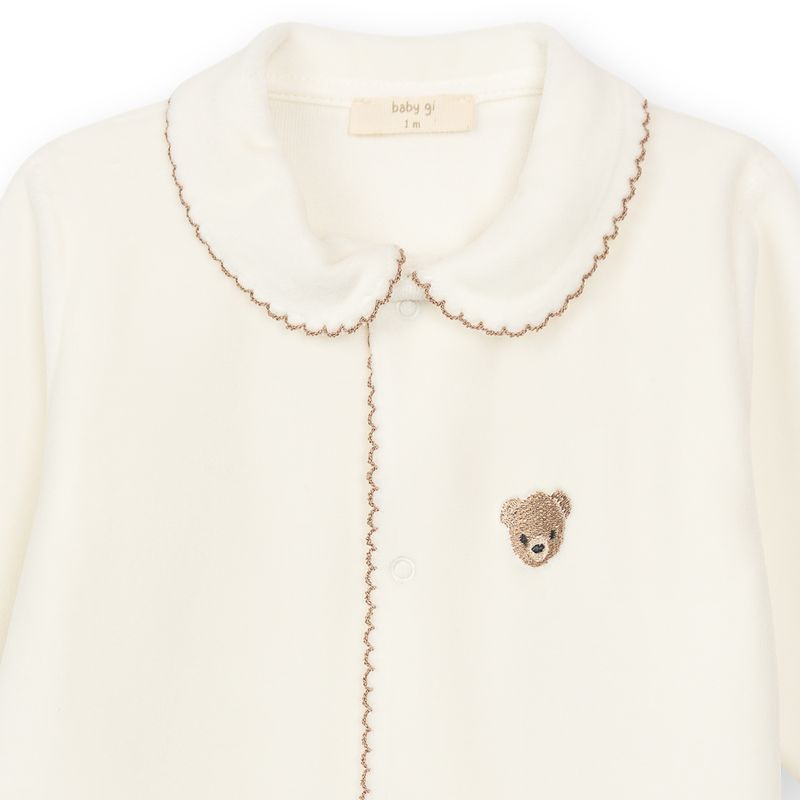 detail van velours babypakje in offwhite met picot rand in camel en teddybeer borduring