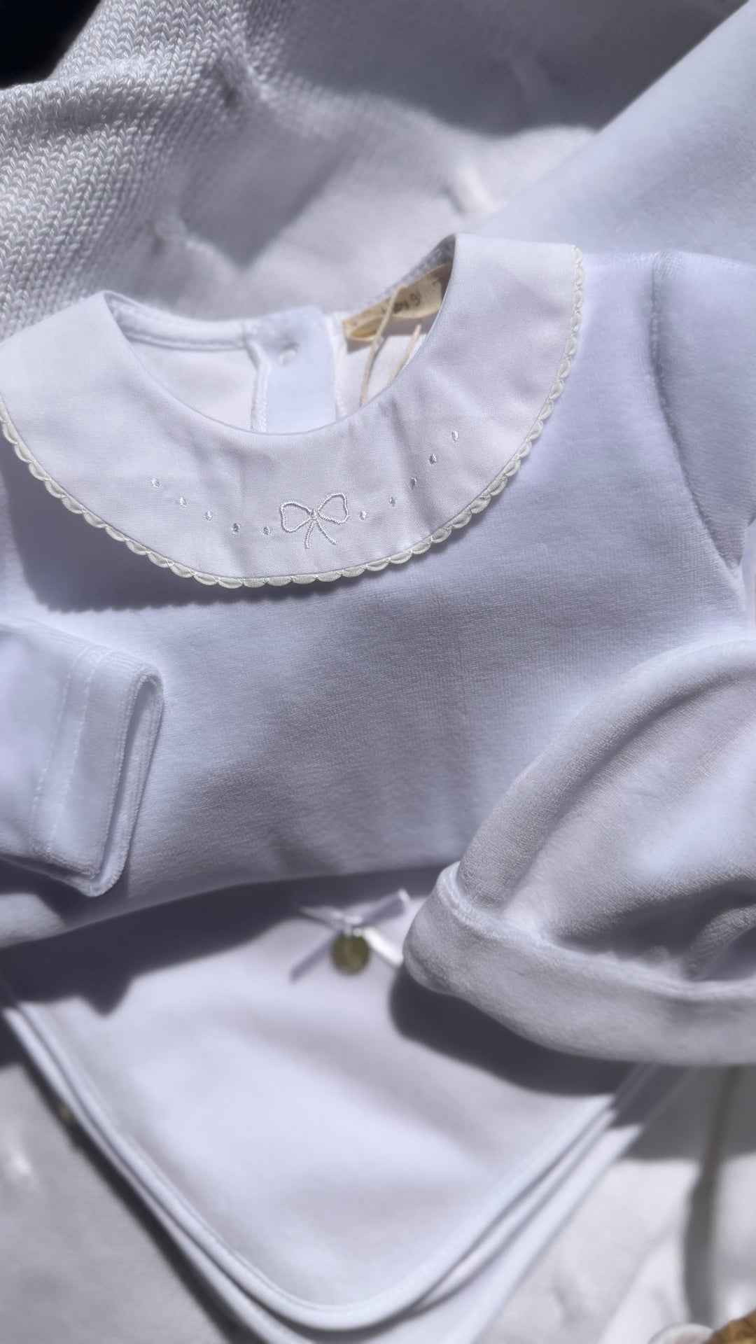 Velours wit babypakje met geborduurde strik op de ronde kraag van baby gi 