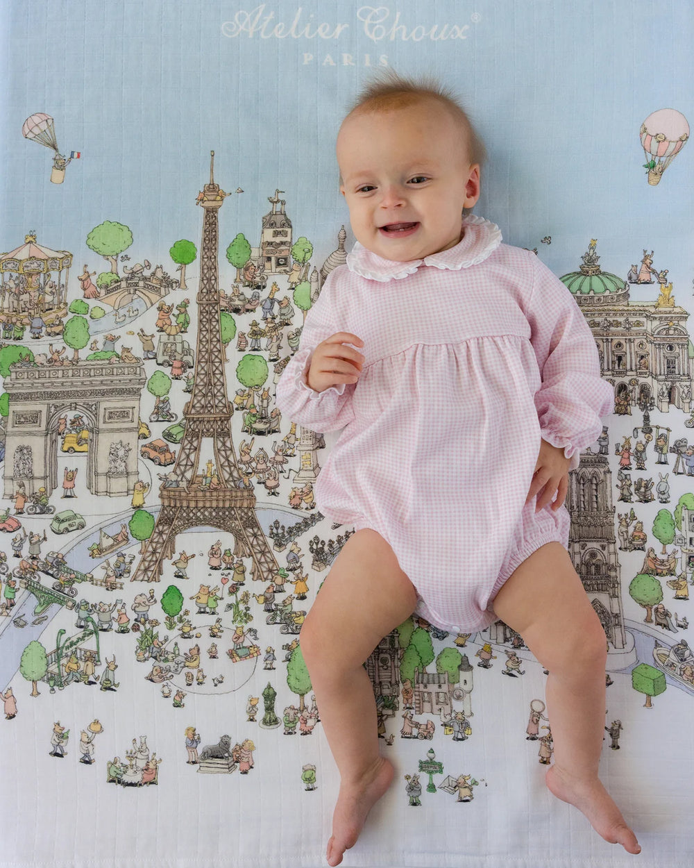 Baby liggend op Atelier Choux Carré Paris met illustraties van de Eiffeltoren, Notre-Dame en Arc de Triomphe