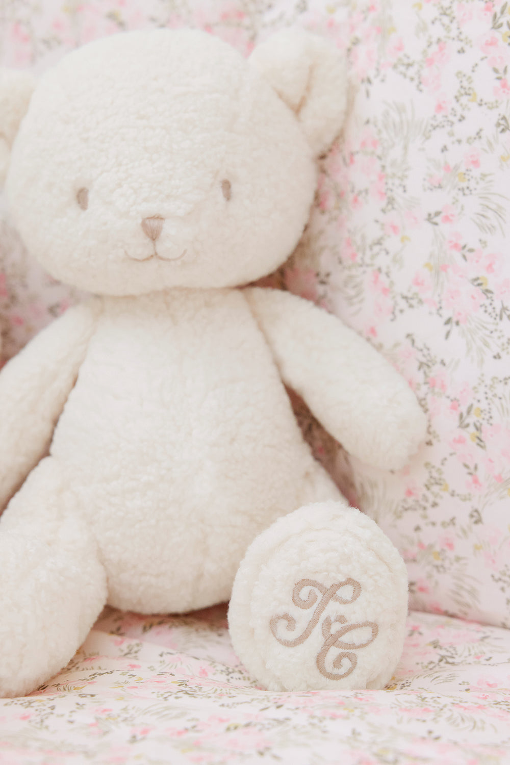 Teddybeer pluche wolf met Tc logo op beddengoed met bloemetjes