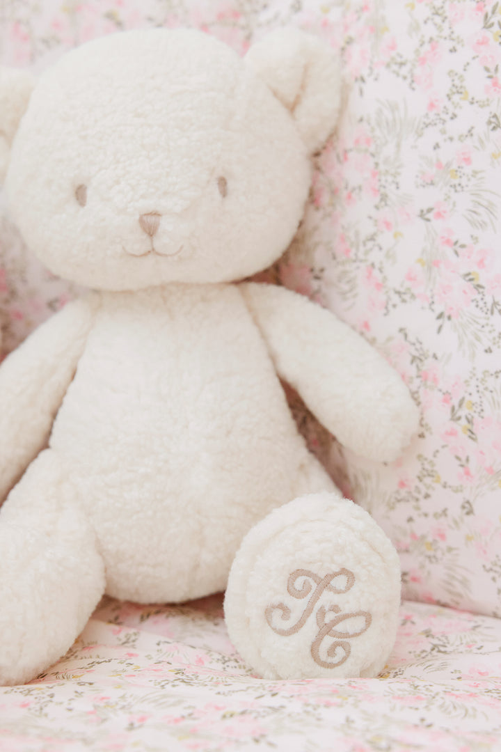 Teddybeer pluche wolf met Tc logo op beddengoed met bloemetjes